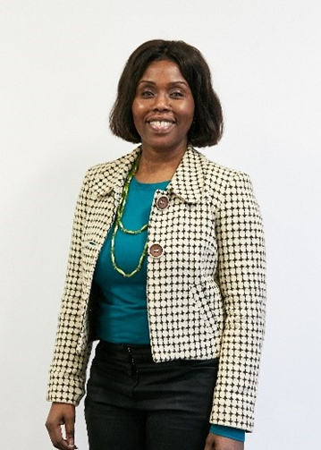 Councillor Evelyn Akoto, a Black woman with mid-length black hair, wearing a cream jacket over a green top and black trousers